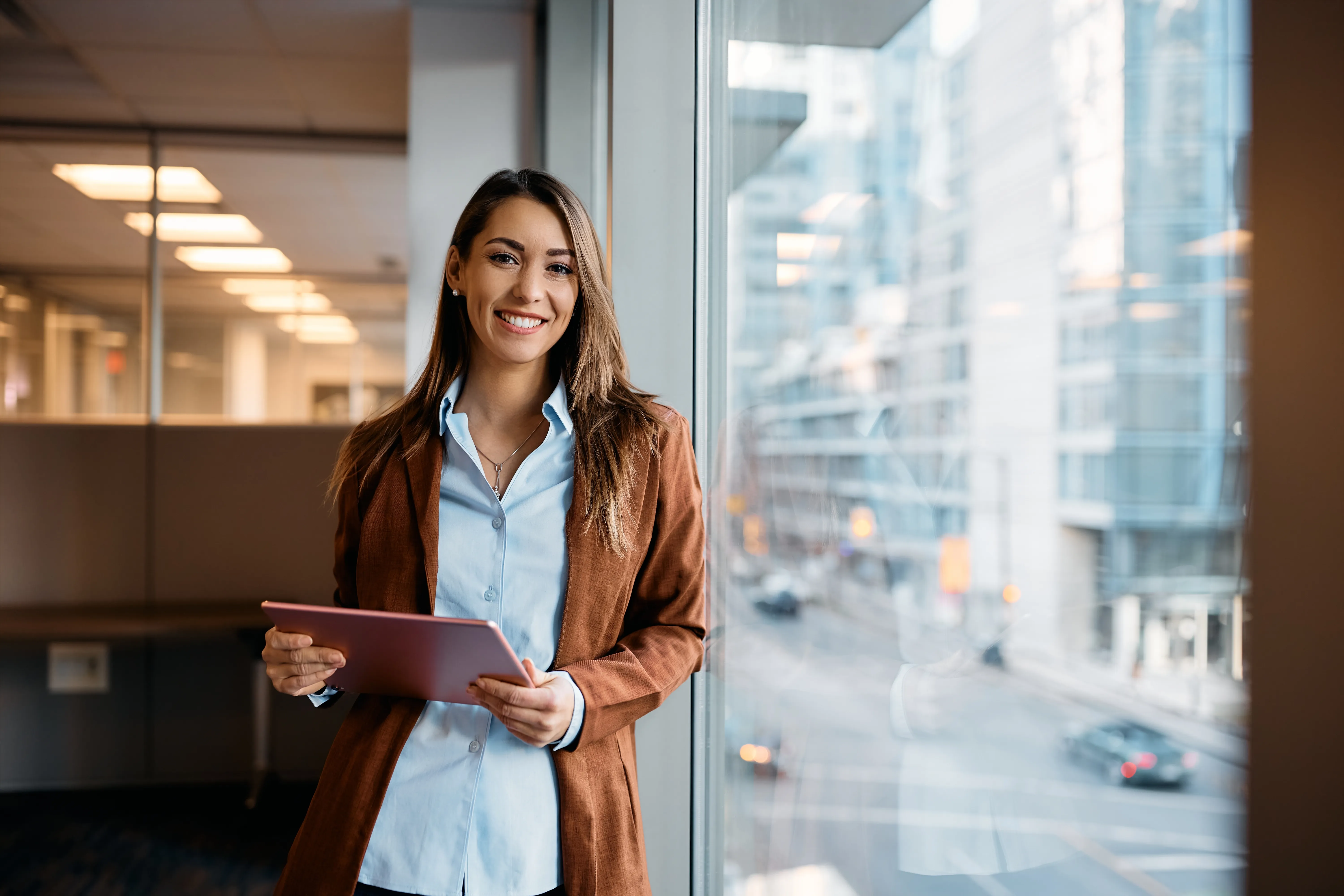 Femme d'affaires souriante avec une tablette au bureau