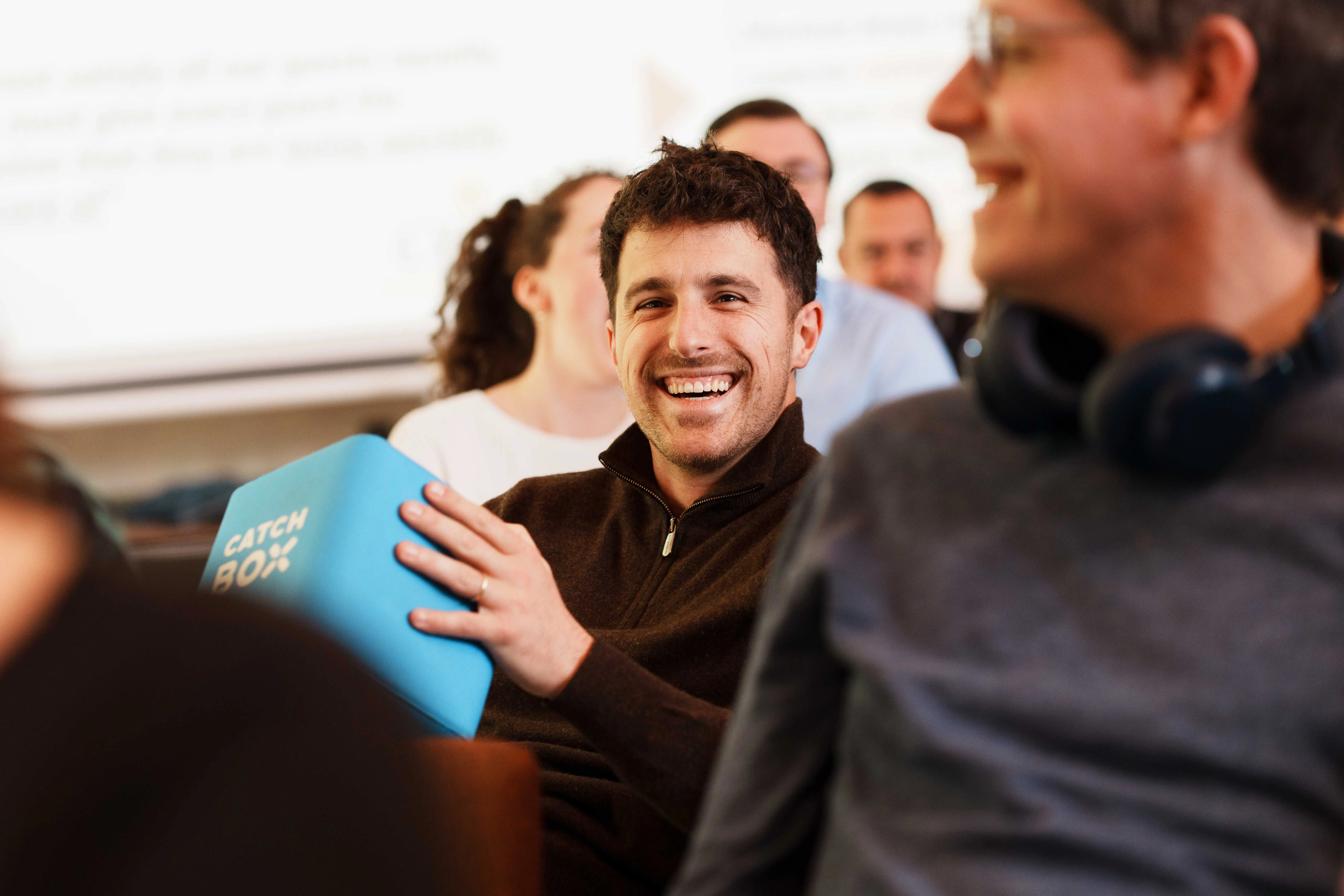 Quatre collègues divers marchant et riant dans un couloir de bureau