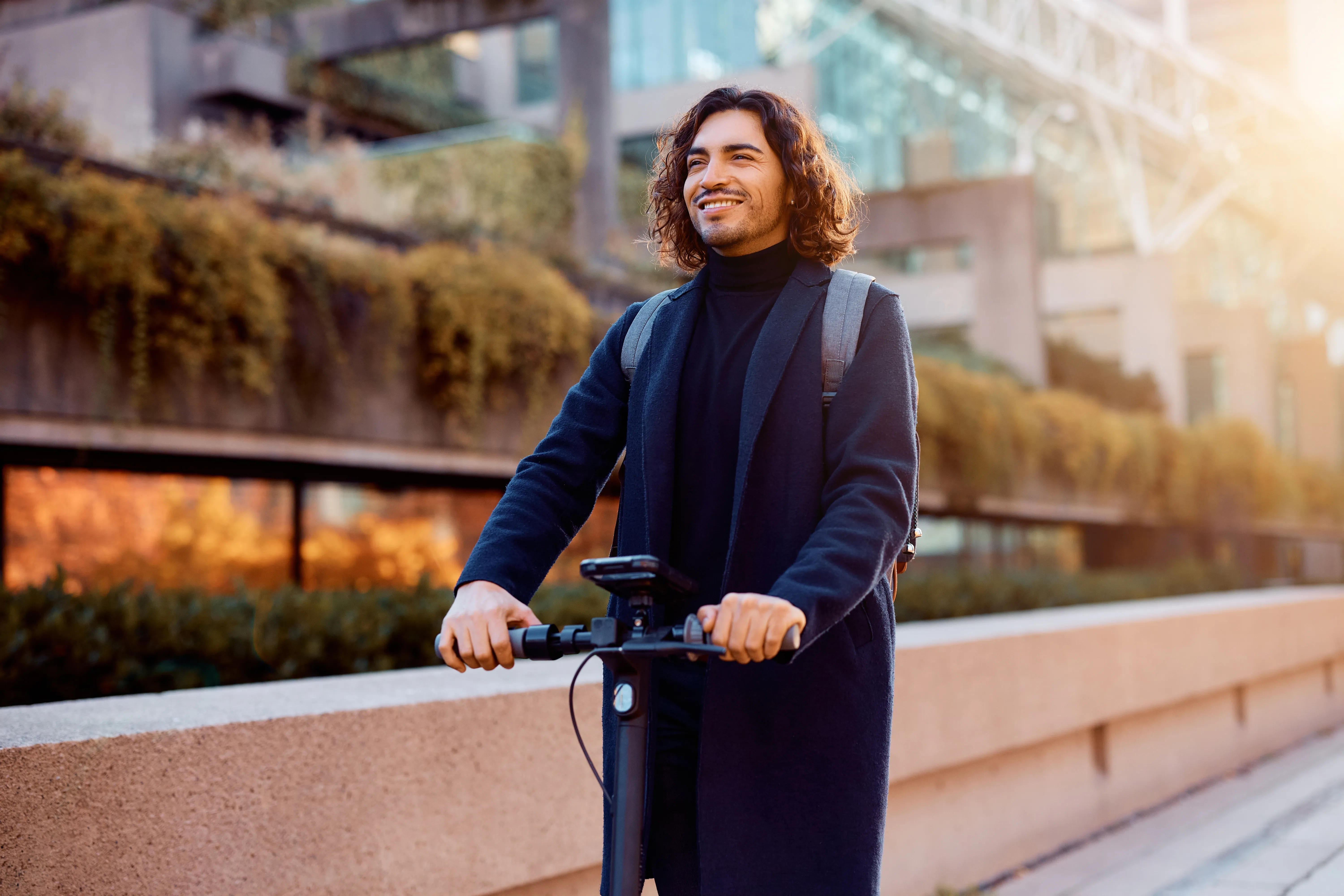 Homme souriant sur une trottinette électrique en ville