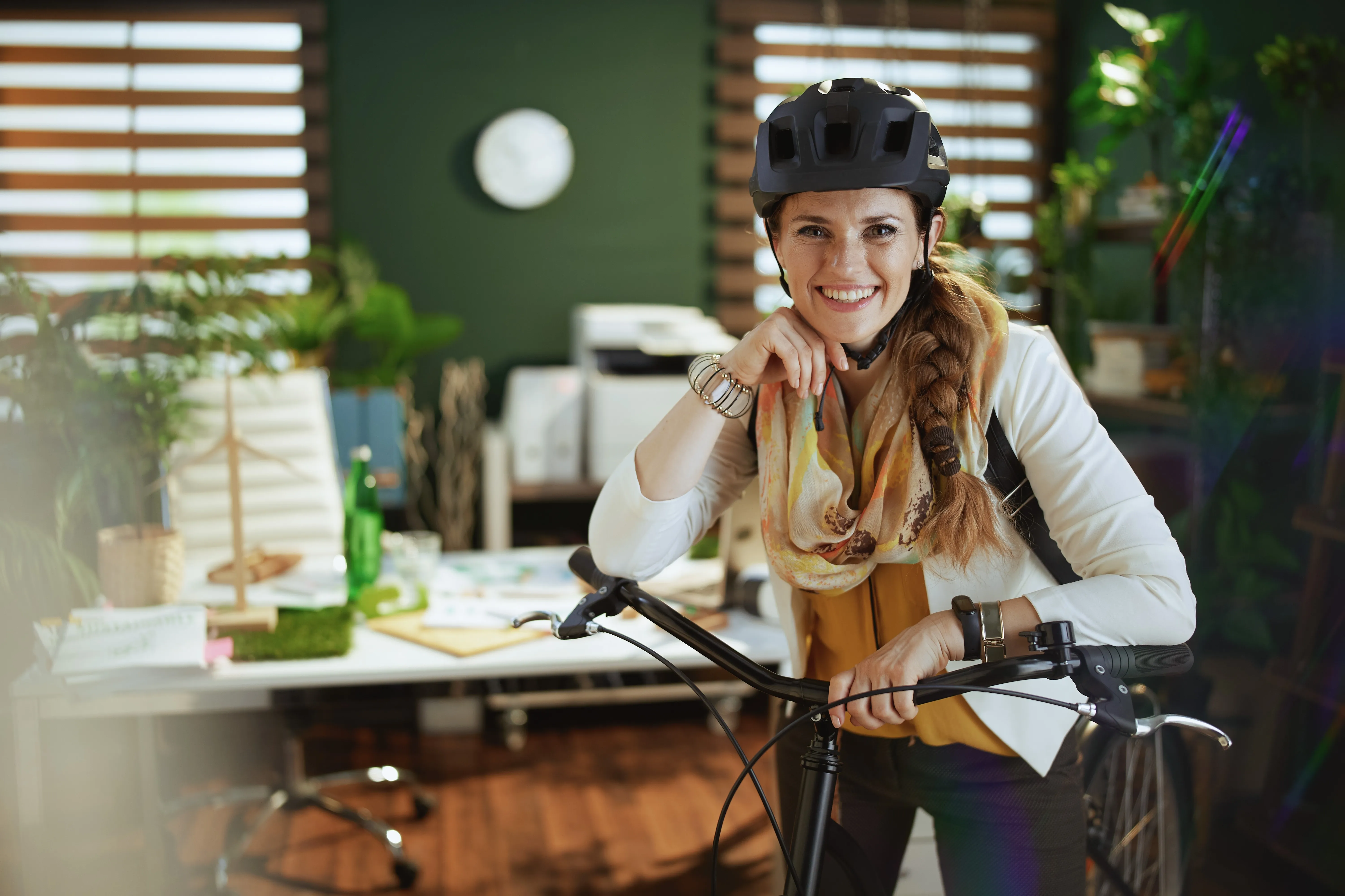 Femme souriante avec un vélo au bureau -- mobilité écologique