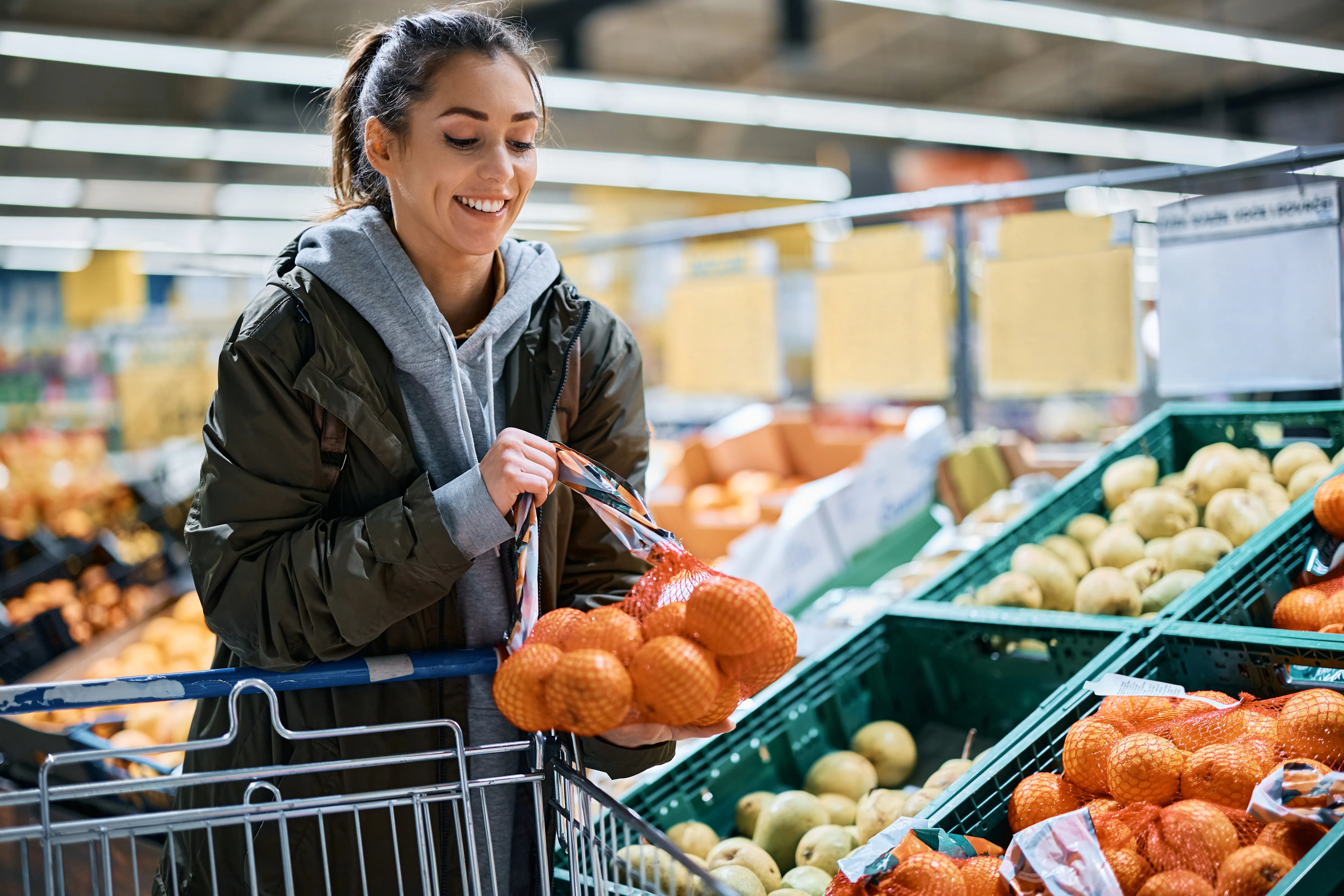 Femme choisissant des fruits au supermarché avec un caddie